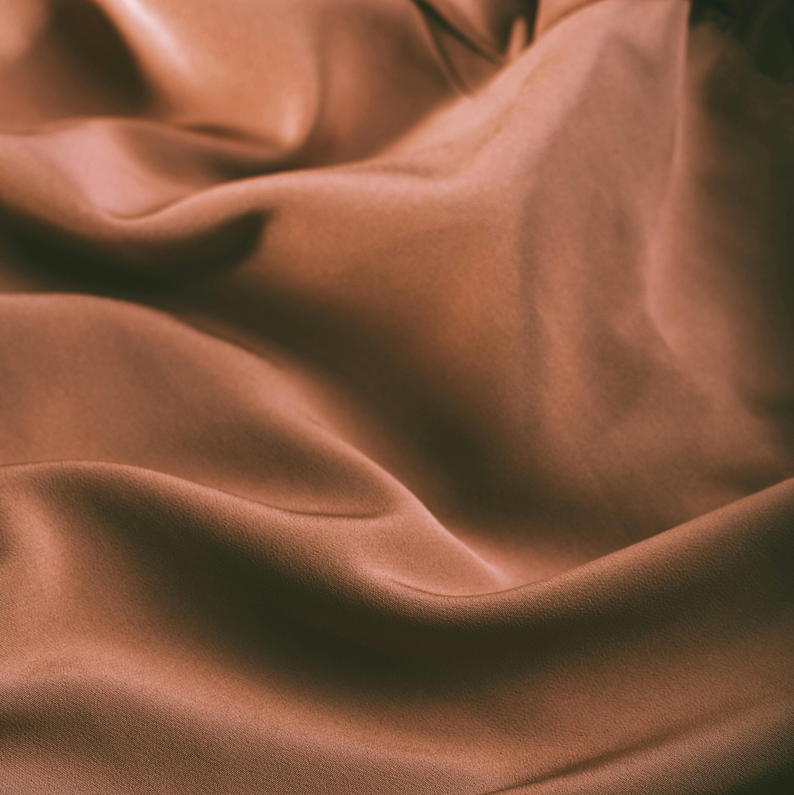 From above of elegant brown draped silk fabric with smooth texture as abstract background